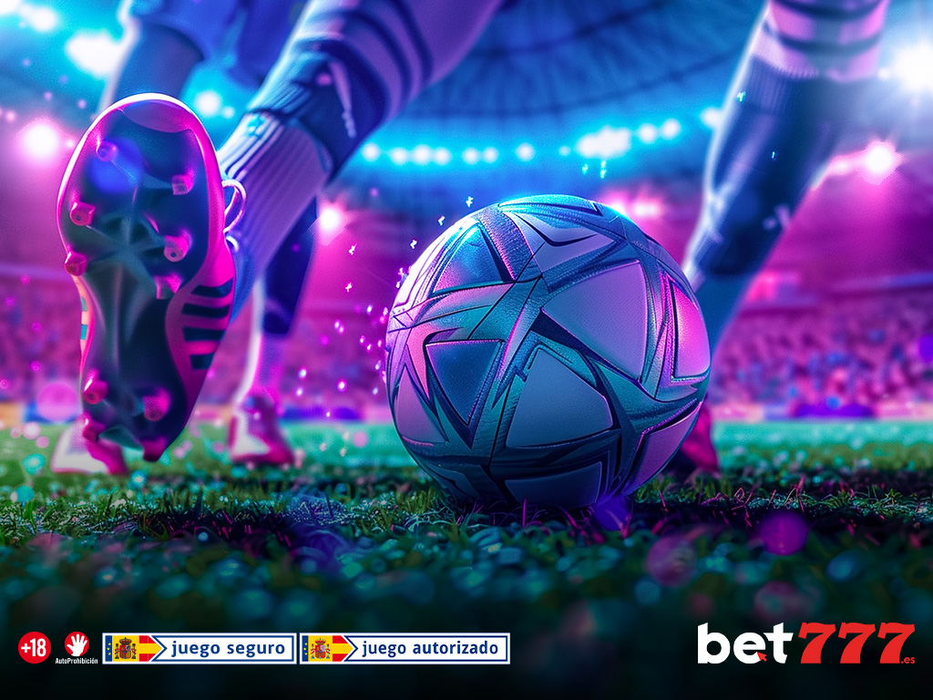 Balón y botas de fútbol en un campo iluminado de noche.
